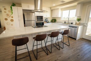 A modern kitchen with a large island, stainless steel appliances, and bar stools.