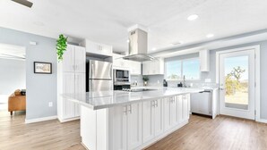 A modern kitchen with white cabinetry, stainless steel appliances, and a large island.