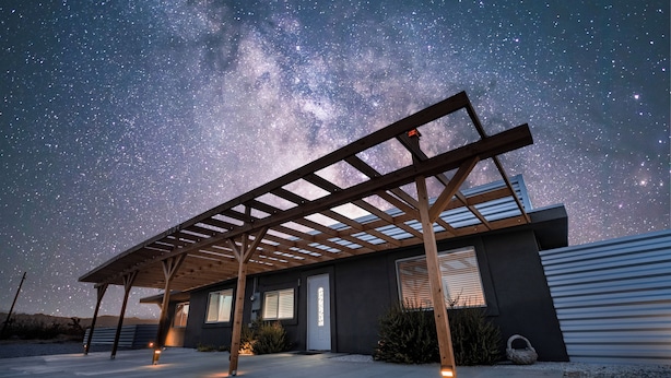 A modern house with a covered patio under a starry sky.