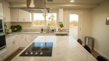 Una cocina moderna con una isla central, electrodomésticos de acero inoxidable y vistas a un paisaje desértico.