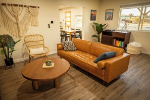 Un salon chaleureux avec un canapé en cuir, une table basse ronde en bois et un fauteuil en osier.