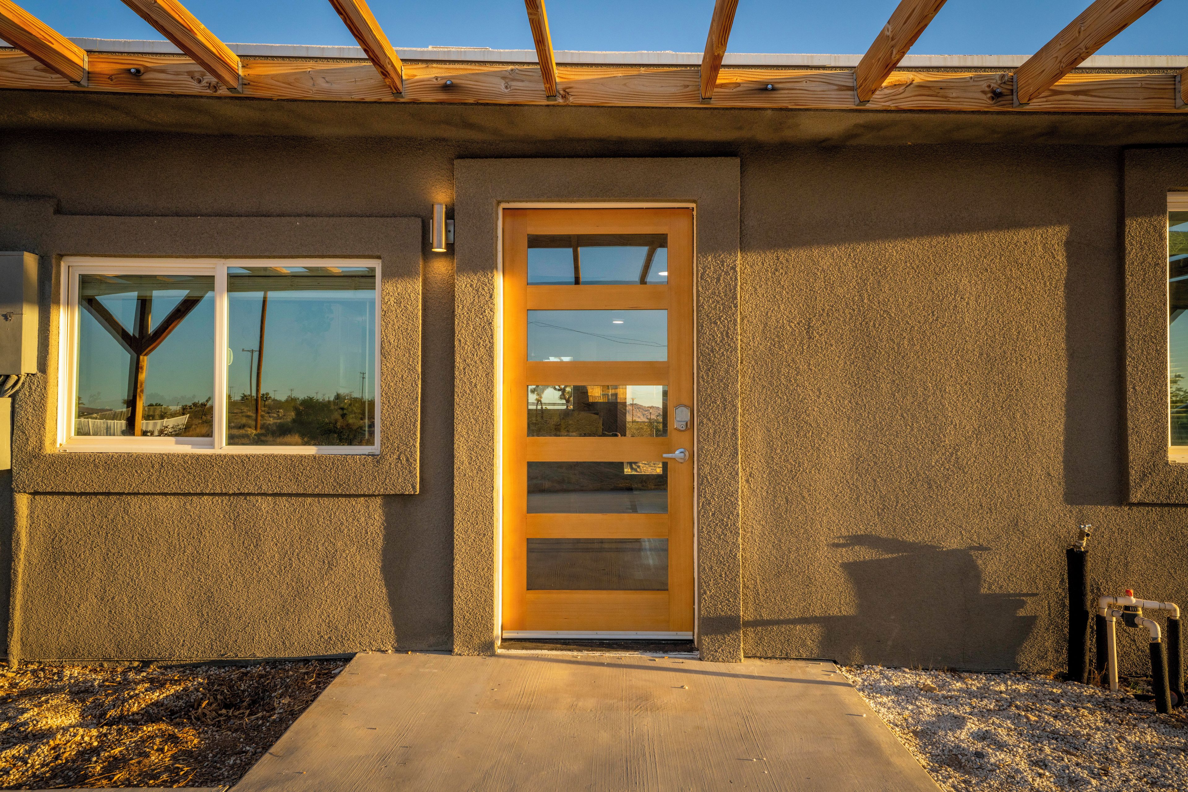 Un edificio con techo de madera, pared exterior texturizada y puerta con ventana.