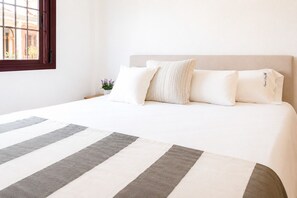 A neatly made bed with striped bedding, a headboard, and two pillows.