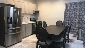 Cocina compacta con comedor, que incluye electrodomésticos de acero inoxidable, lavavajillas y una mesa de comedor con sillas.