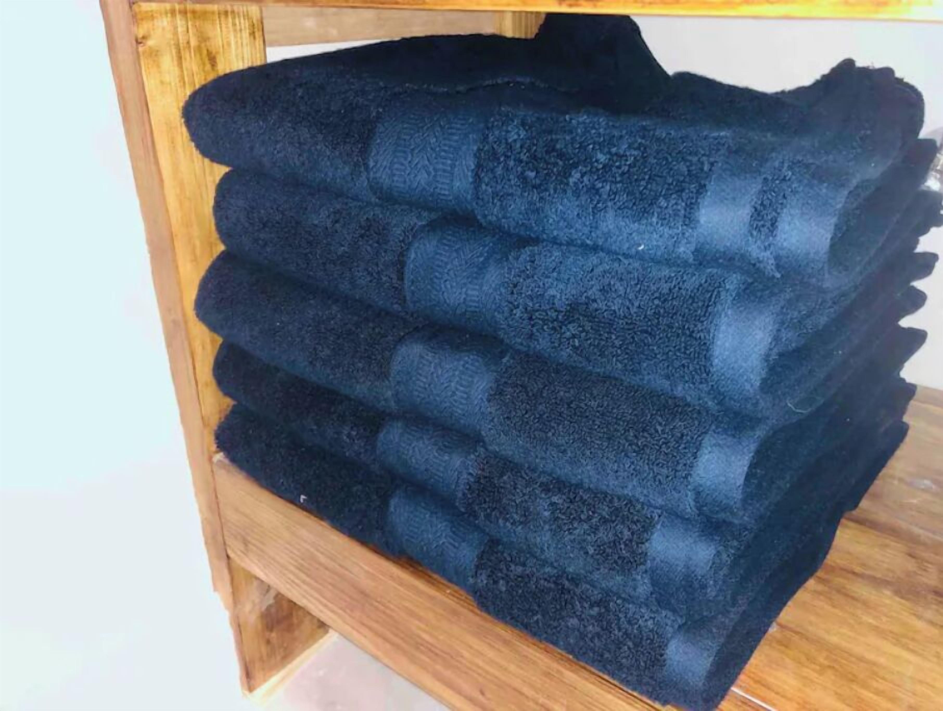 A stack of dark blue towels on a wooden shelf.