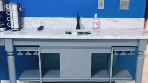 Una cocina con encimera de mármol, fregadero y estanterías empotradas.