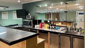 A modern kitchen with a central island, built-in microwave, and a glass-fronted bar area with shelves of glasses. - Spacious 4 bedroom- Great Location (Lexington)