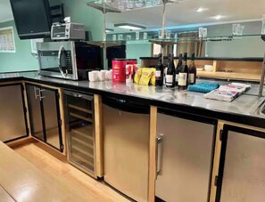 A kitchen area with a microwave, coffee maker, and various kitchen appliances. There are also several bottles and a blue cloth on the counter.