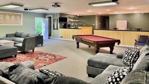 A modern living room with a pool table, grey sofas, and a kitchen area. - Spacious 4 bedroom- Great Location (Lexington)