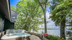 Un jacuzzi con pared de piedra y vista al lago.