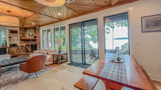 Amplia sala de estar con techo de madera, chimenea de piedra y grandes puertas correderas que dan a un patio exterior.