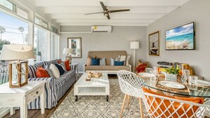 A modern living room with a sofa, coffee table, and dining area. - "WAVE POOL" HOUSE! 1-Short Block to Ocean! (Oceanside)