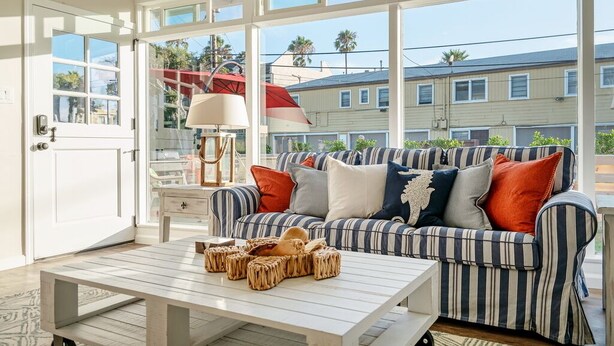 A room with a striped sofa, a wooden coffee table, and a lamp. - "WAVE POOL" HOUSE! 1-Short Block to Ocean! (Oceanside)