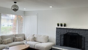 Una sala de estar con sofá modular, mesa de centro, chimenea y una bola de discoteca.