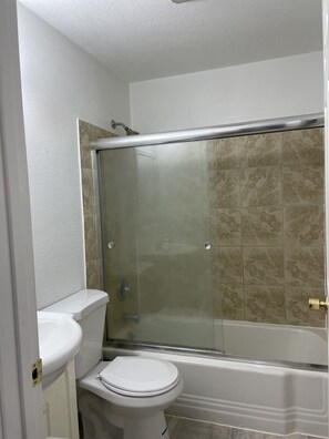 A bathroom with a glass-enclosed shower, a white toilet, and a bathtub.