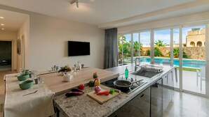 A modern kitchen with a large island, a built-in oven, and a view of a swimming pool. - Wellness Hygge Modern Gozitan Apartment (Xaghra)