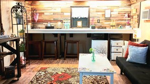Eine gemütliche Küche mit Holzelementen, ein Essbereich mit einem floralen Teppich und eine Bar mit Sitzhocker.