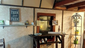 Ein rustikales Interieur mit Holzböden, Regalen mit landwirtschaftlichen Gegenständen, einem Holztisch und einem Metall-Pflanzgefäß.