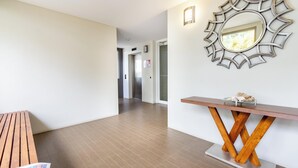 A hotel lobby with a wooden bench, a sun-shaped mirror, and a wooden console table. - Awesome, modern, open-plan 3rd floor (with lift) unit with stunning water views. (Bongaree)
