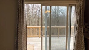 Ein Zimmer mit einer Schiebeglastür, die auf eine Holzterrasse führt.
