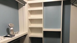 Ein Schrank mit mehreren Regalen und einem kleinen Tisch, auf dem eine Wasserflasche und Papiere stehen.