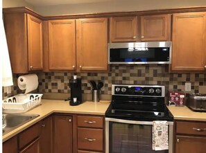 Fully equipped kitchen with a stove, microwave, coffee maker, and ample storage.