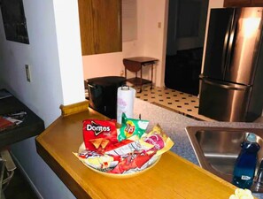 Eine Küche mit Holzarbeitsplatte, einer Chips-Schüssel, einem Kühlschrank und einem Spülbecken.