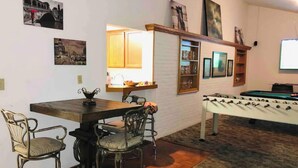 A cozy living room with a wooden dining table, two chairs, a foosball table, and a television. - Location!! Close to Everything! Spacious and Fun! (Lexington)