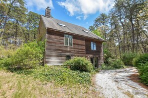 Eine Holzhütte mit Kiesweg, umgeben von dichtem Wald.