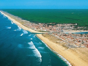 Une vue aérienne d’une ville côtière, avec une plage, des bâtiments et un ciel dégagé.