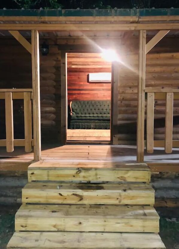 Een houten blokhut met een trap die leidt naar een kamer met een groene bekleden bank.