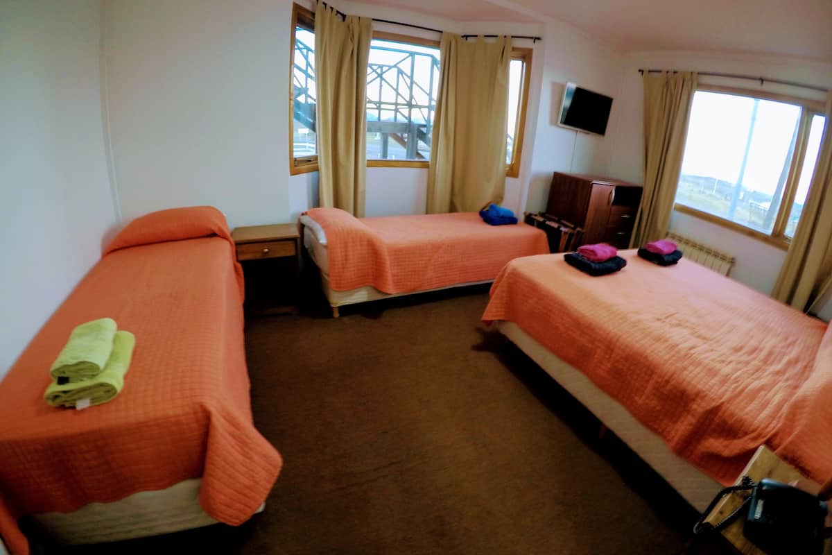 A hotel room with two beds, a TV, and a window with curtains.