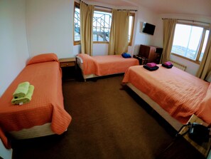 A hotel room with two beds, a TV, and a window with curtains.