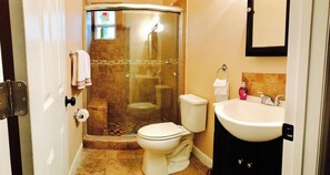 Un baño con cabina de ducha, inodoro, lavabo y espejo.