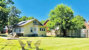Eingeschossiges Haus mit gepflegtem Rasen und drei Korbstühlen.