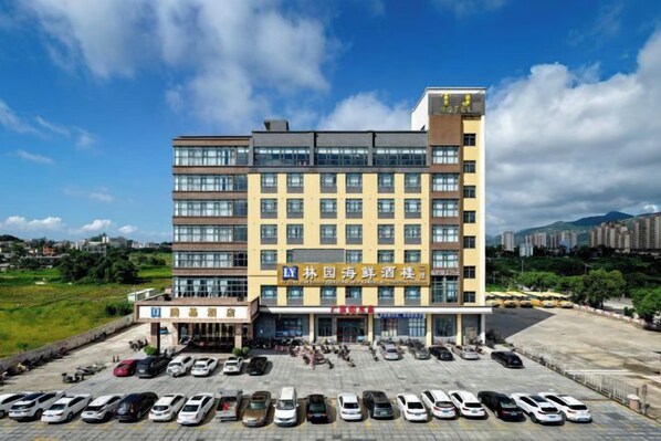 A multi-story hotel with a parking lot in front. - Tengji Hotel (Taishan)