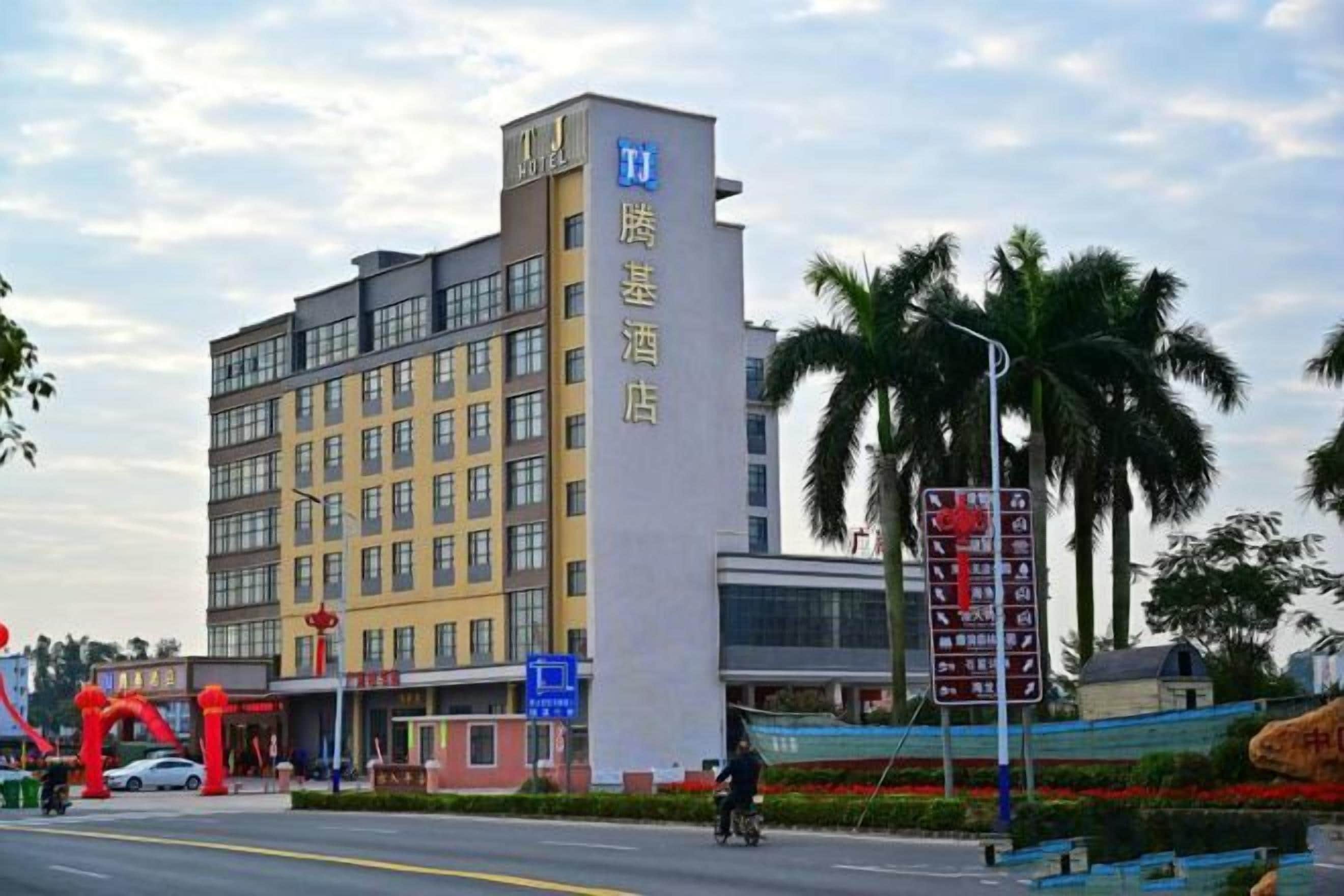 A multi-story hotel with a prominent sign, a road with a cyclist, and palm trees in the background.