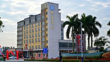 A multi-story hotel with a prominent sign, a road with a cyclist, and palm trees in the background.