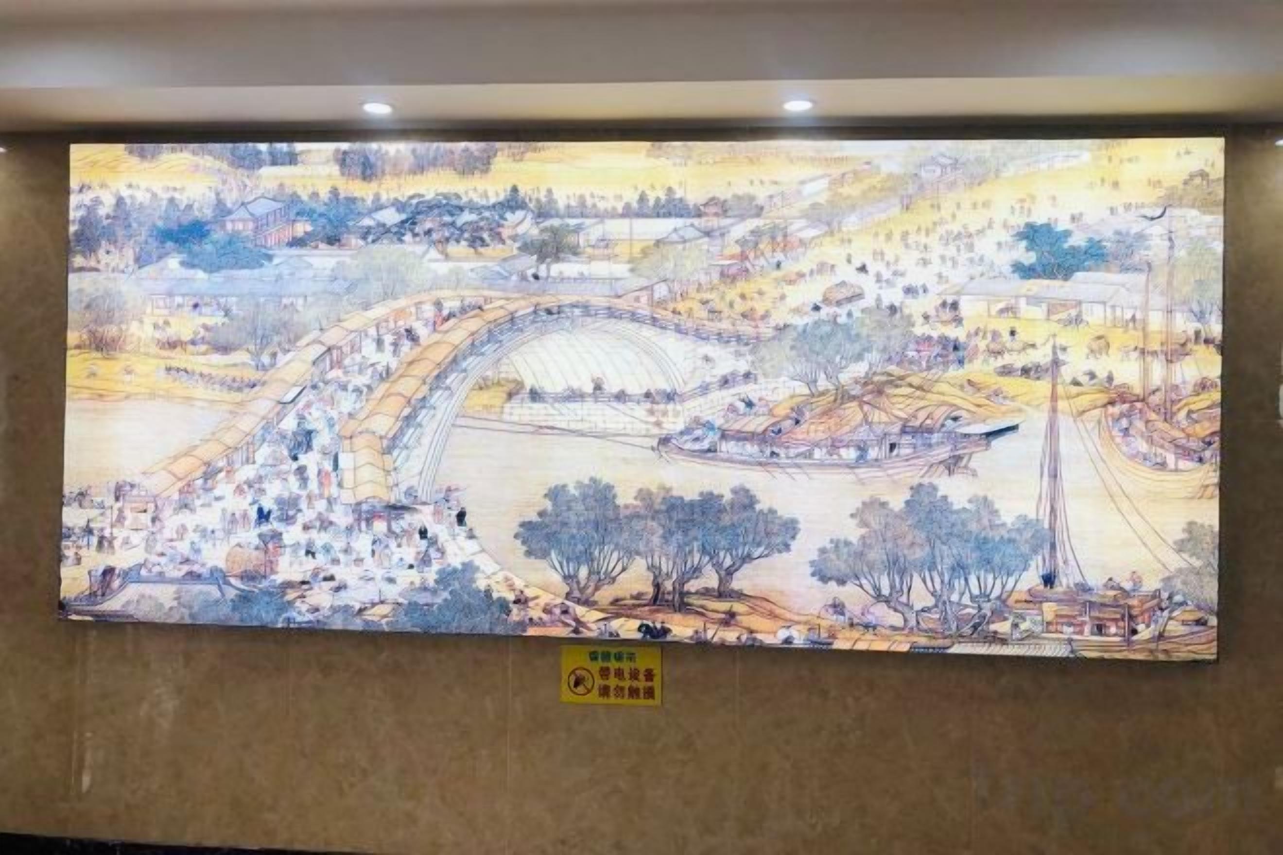 A large wall mural depicting a landscape with a river, buildings, and trees.