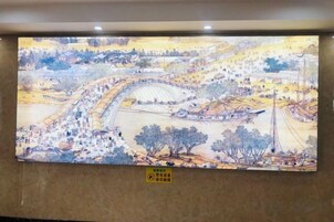 Un gran mural que representa un paisaje con río, edificios y árboles.