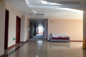 A hotel corridor with a polished floor, a sofa with a red cushion, and a sign on the wall.