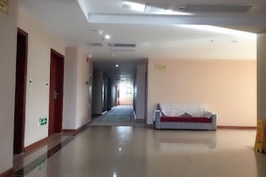 A hotel corridor with a sofa, doors, and a sign. - Tengji Hotel (Taishan)