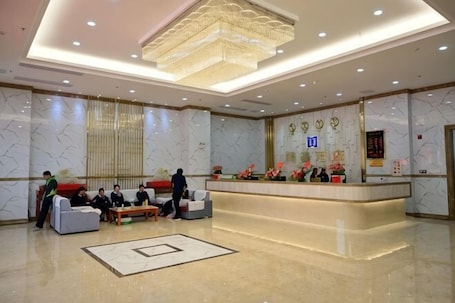 A hotel lobby with a reception desk, seating area, and a large chandelier.. Tengji Hotel