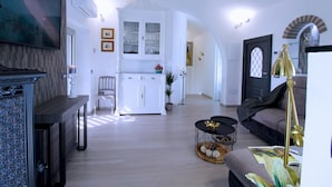 A spacious living area with a fireplace, a dining area with a white cabinet, and a cozy seating area with a lamp.