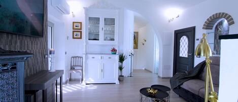 A spacious living area with a fireplace, a dining area with a white cabinet, and a cozy seating area with a lamp.