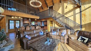 A spacious living room with leather sofas, a marble coffee table, and a staircase leading to an upper level. - Romantic Sunset Lakefront View, Minutes to the Slopes and Village! (Big Bear Lake)