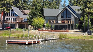 A lakeside property with a dock, a large house with a balcony, and surrounding trees. - Romantic Sunset Lakefront View, Minutes to the Slopes and Village! (Big Bear Lake)