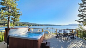 A deck with a hot tub, outdoor seating, and a view of a lake and mountains. - Romantic Sunset Lakefront View, Minutes to the Slopes and Village! (Big Bear Lake)