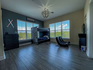 Une chambre avec un lit superposé, un fauteuil massant et un bureau.