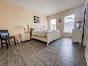 Quarto com cama, mesa de cabeceira, cadeira e cômoda.